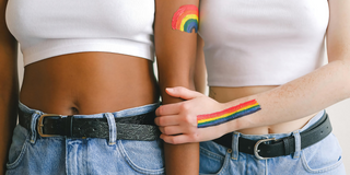 Two people standing next to each other with pride drwaings on arms 